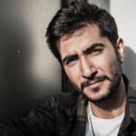 Close-up portrait of a confident man with a beard outdoors, embracing natural light.